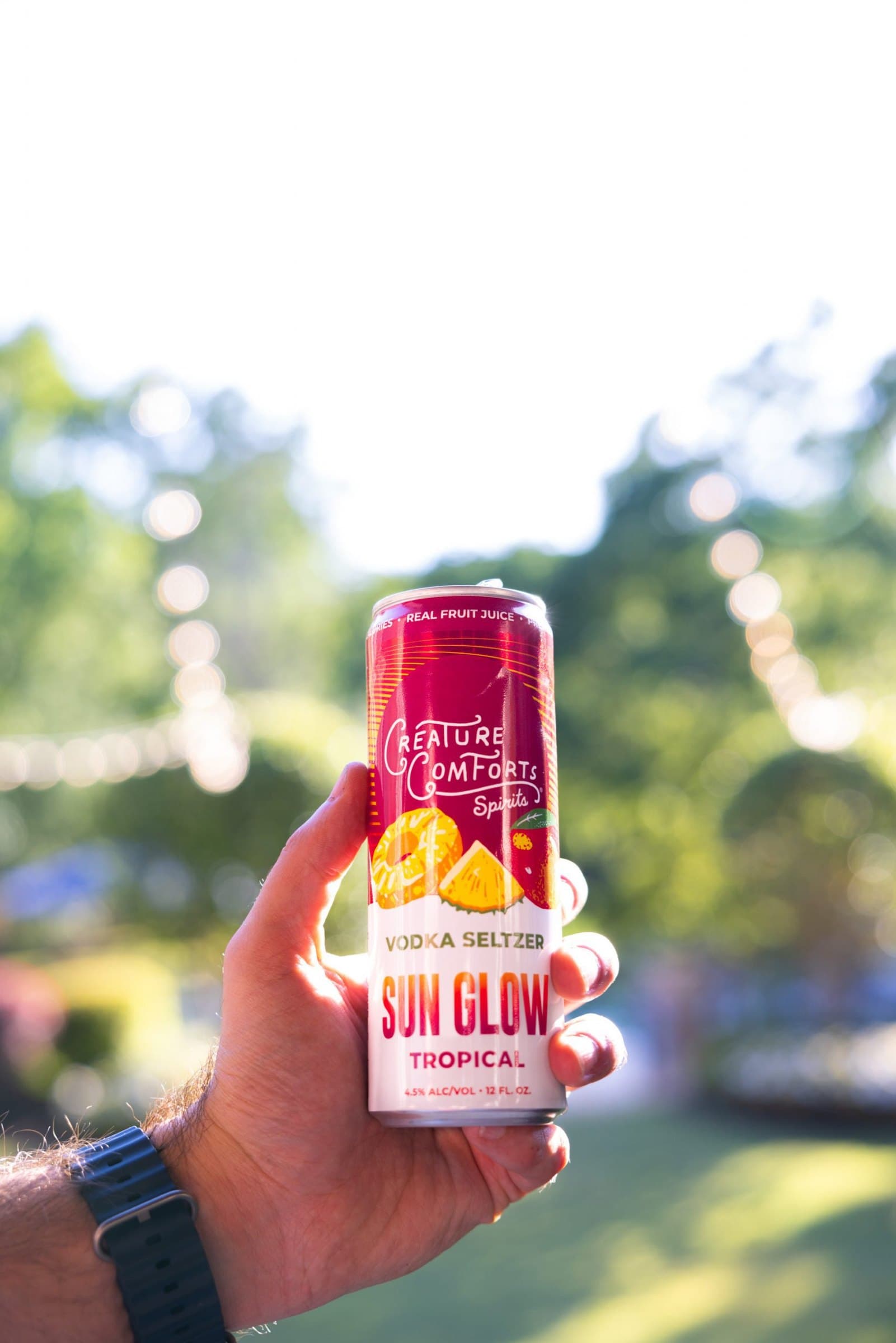 A hand holding a can of Sun Glow Tropical outdoors