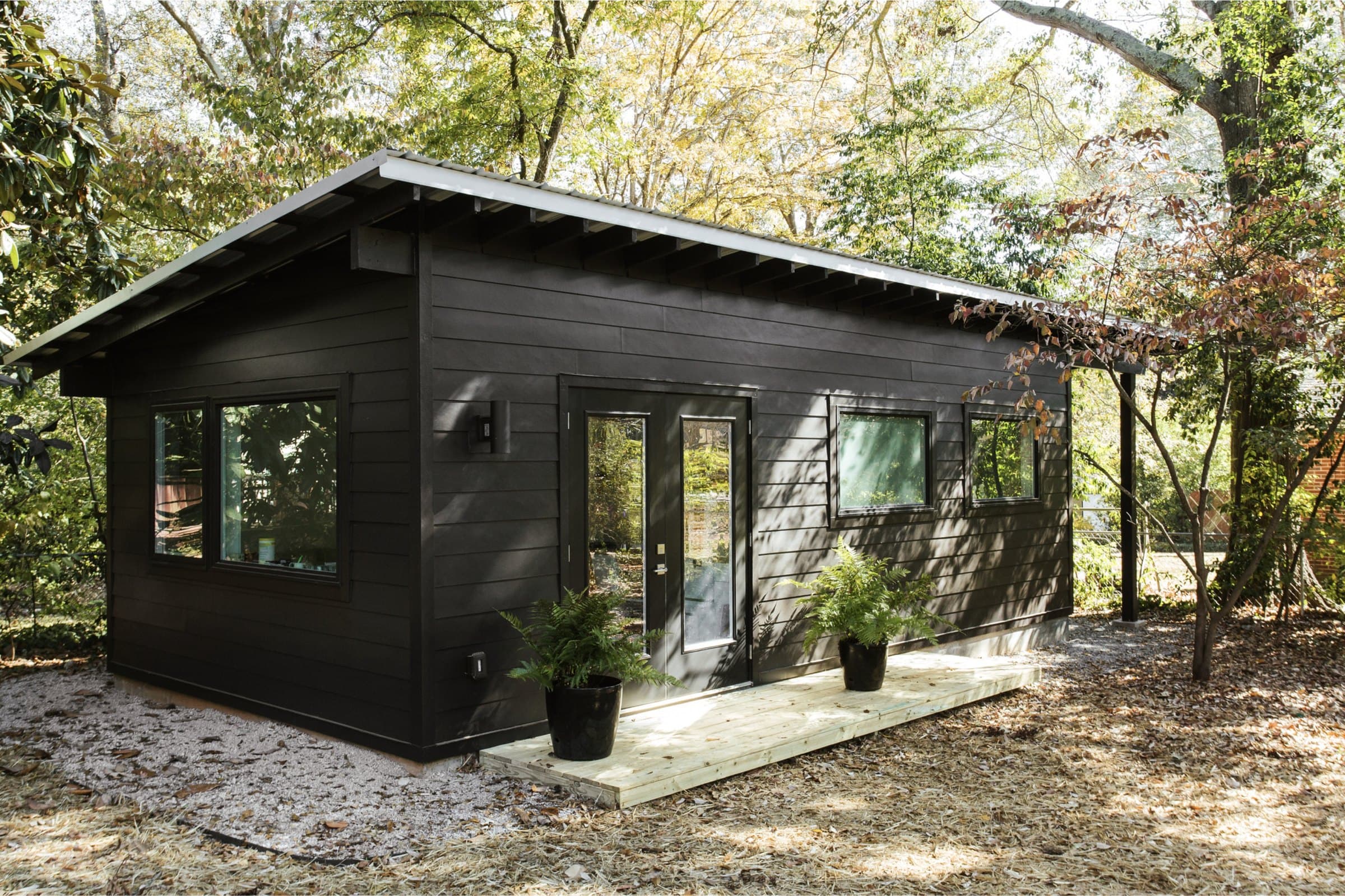 A small black studio building in the woods