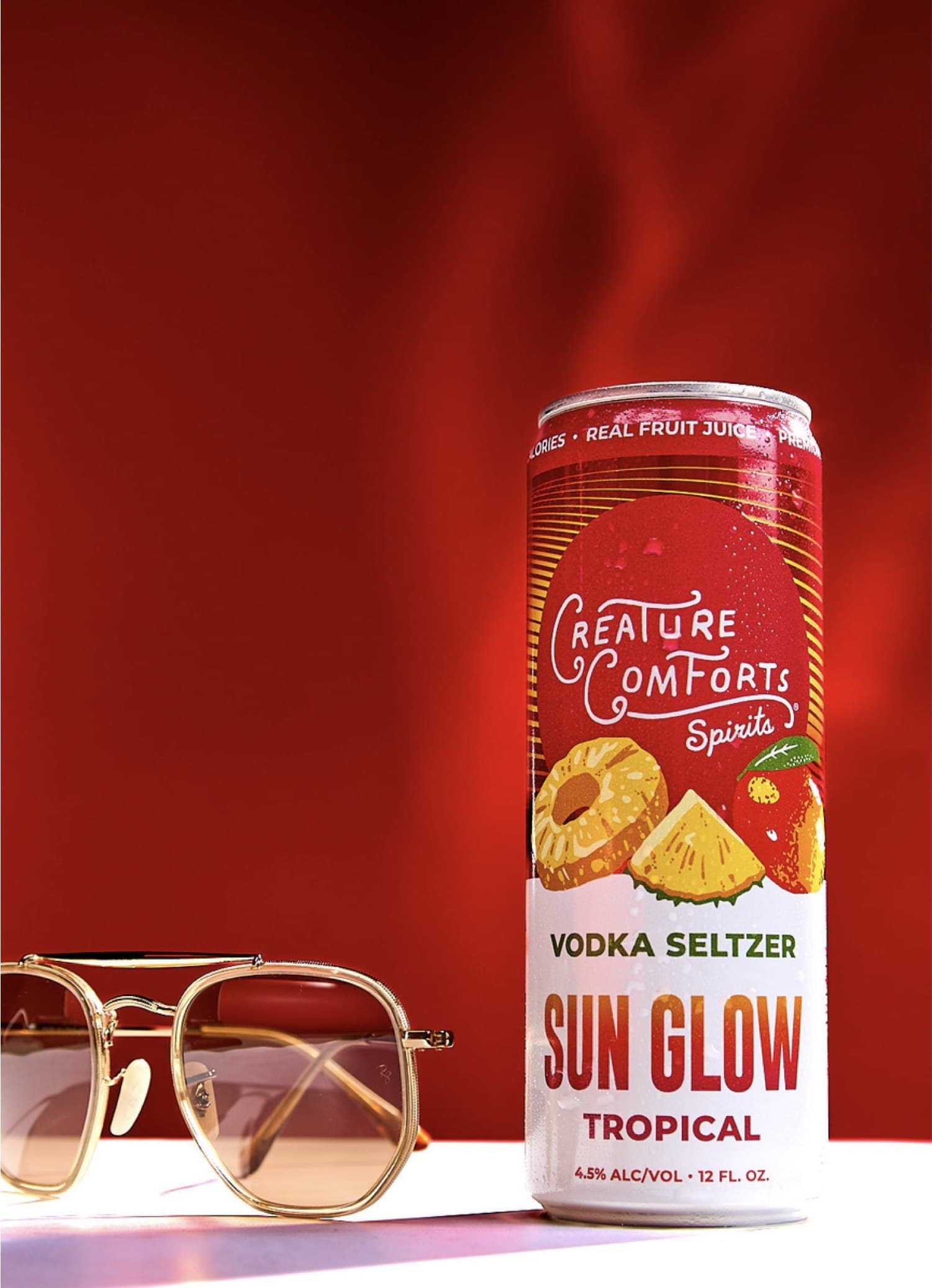 A can of Sun Glow Tropical beside sunglasses on a red set